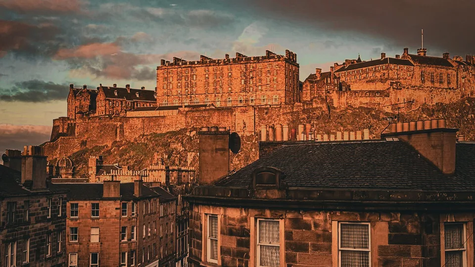Edinburgh Castle on Castle Rock at sunset, seen above the rooftops of the Old Town