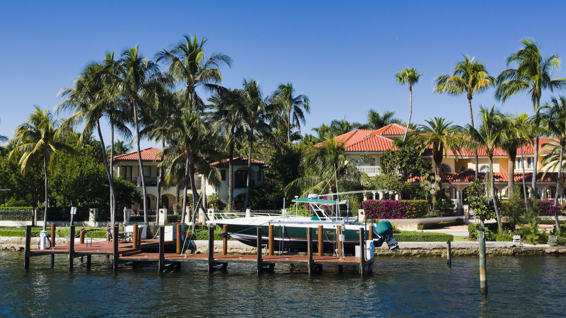 Scenic view of luxury waterfront homes with palm trees and a boat docked in Fort Lauderdale, Florida