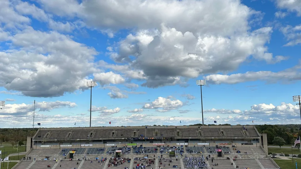 High-angle view of an American football game in a large outdoor stadium under a partly cloudy sky