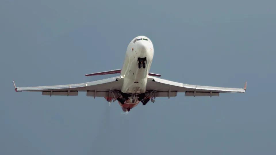 A commercial jet taking off into a dramatic sky, climbing above the runway