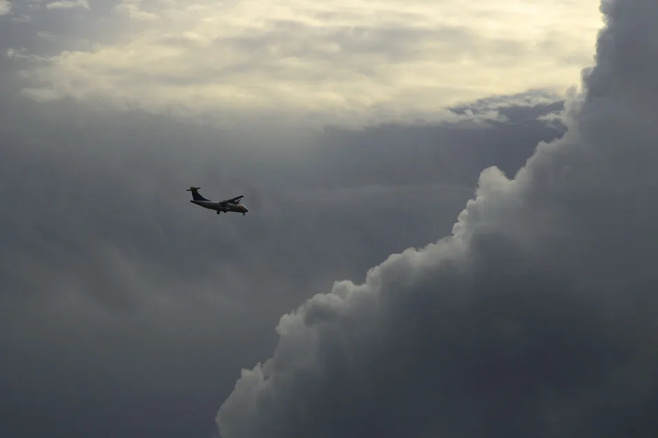 An airplane navigating a turbulent sky surrounded by dramatic storm cloud formations